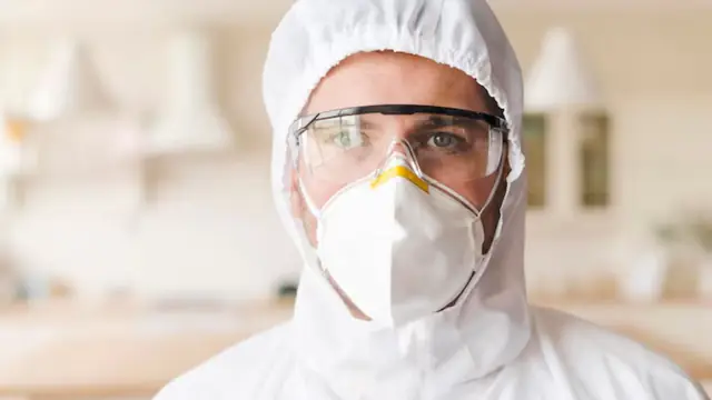 Mold remediation professional in a respirator and protective hood