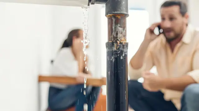 Tenants reporting a leaking pipe by phone while water runs down it