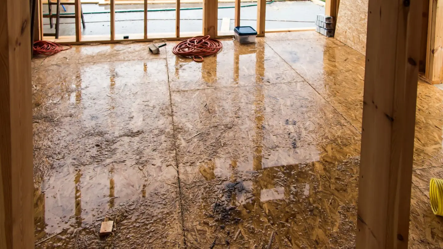 Water-stained wood subfloor with open framing after water damage