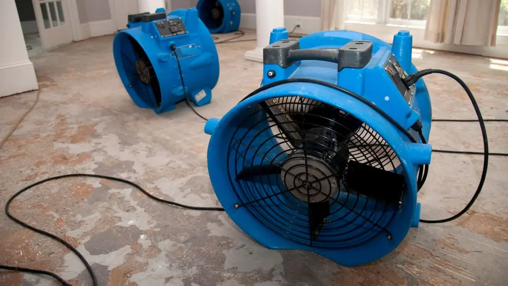 Blue air mover running on a floor after flood water was removed